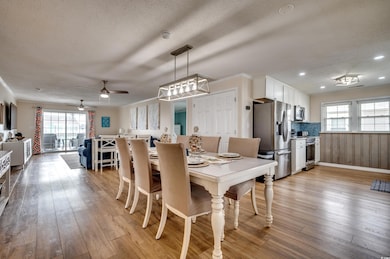 Dining area with healthy amount of natural light, a ceiling fan, light wood finished floors, recessed lighting, and a textured ceiling