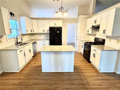 Kitchen featuring black appliances, backsplash, and lofted ceiling
