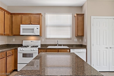 Kitchen with white appliances, a sink, brown cabin