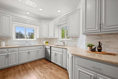 Kitchen featuring decorative backsplash, light stone countertops, light wood-type flooring, white cabinetry, and recessed lighting