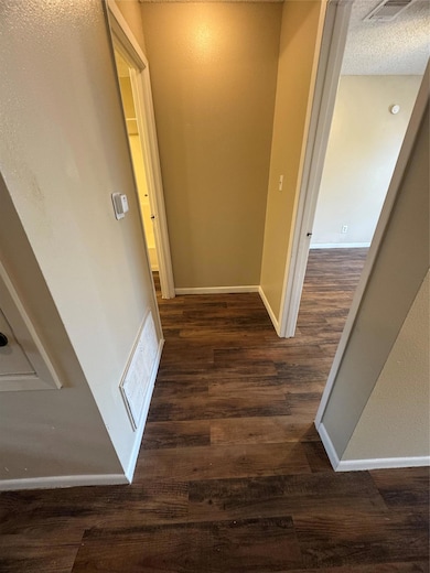 Hallway featuring dark wood finished floors, base