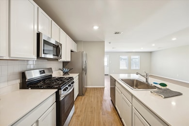 The modern kitchen features sleek stainless appliances, with white cabinets