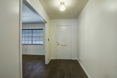 Front entry is flanked by formal living with lovely wood tile floors.