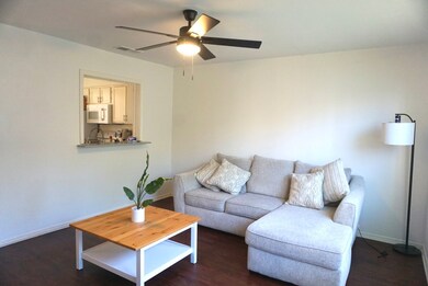 Living area with dark wood-style floors and ceiling fan