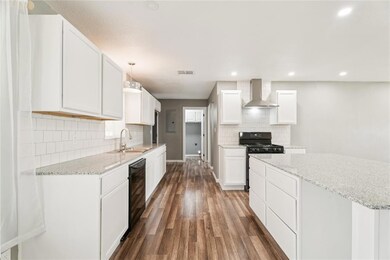 Kitchen featuring wall chimney exhaust hood, a sink, black gas range oven, dark wood finished floors, and backsplash