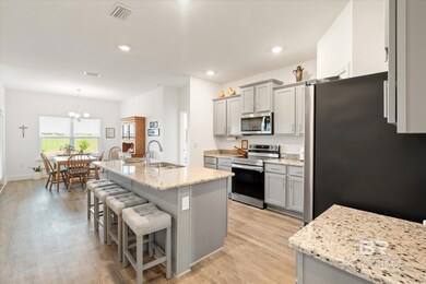Kitchen with visible vents, a breakfast bar, gray cabinets, a sink, and appliances with stainless steel finishes