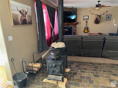 Living room with a wood stove, ceiling fan, and a fireplace