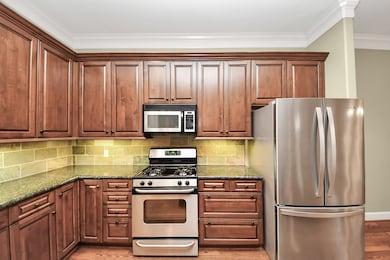 This kitchen features elegant wooden cabinets, stainless steel appliances including a refrigerator and gas stove.