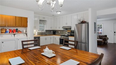 Kitchen featuring separate washer and dryer, appliances with stainless steel finishes, butcher block countertops, backsplash, and a chandelier
