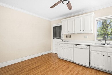 Kitchen with dishwasher, a sink, a ceiling fan, white cabinetry, and crown molding