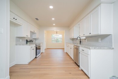 Kitchen with appliances with stainless steel finishes, light wood-type flooring, recessed lighting, decorative backsplash, and white cabinetry