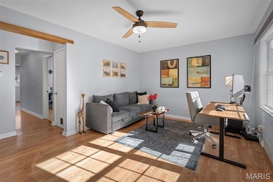 Living area featuring a desk, light wood-style floors, and ceiling fan