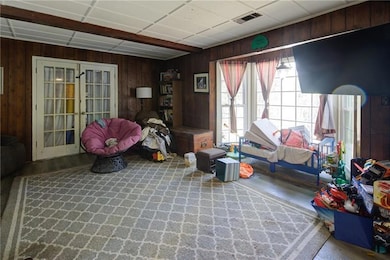 Rec room featuring french doors, wooden walls, wood finished floors, and a paneled ceiling