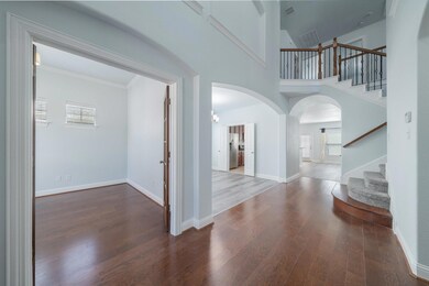 Entryway with wood flooring, a towering ceiling, and ornamental molding