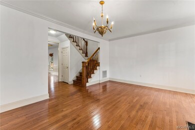 Unfurnished room featuring wood-type flooring, a notable chandelier, and ornamental molding