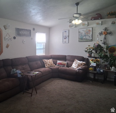Living area with vaulted ceiling, carpet, a ceiling fan, and a textured ceiling