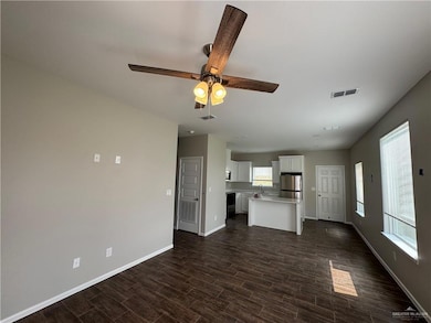 Unfurnished living room with baseboards, dark wood-style flooring, and ceiling fan
