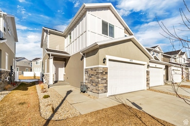 View of front of house with stone siding, a garage, concrete driveway, stucco siding, and a residential view