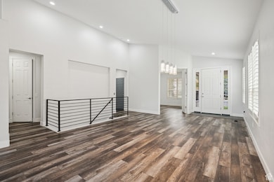 Foyer entrance with high vaulted ceiling, dark wood-style floors, recessed lighting, and a chandelier