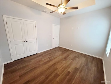 Unfurnished bedroom with wood finished floors, baseboards, a closet, and a ceiling fan