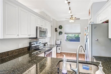 Kitchen featuring white cabinets, appliances with stainless steel finishes, ceiling fan, and hardwood / wood-style floors