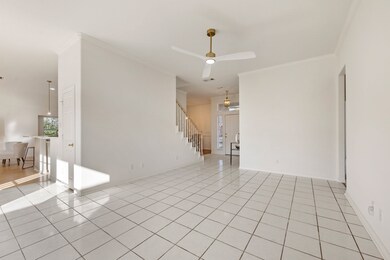 Living room with light tile patterned flooring, crown molding, stairway, and a ceiling fan