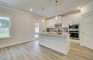 Kitchen featuring stainless steel appliances, under cabinet range hood, healthy amount of natural light, decorative backsplash, and ornamental molding