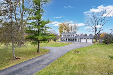 Traditional-style home featuring a porch, a front lawn, asphalt driveway, and a garage