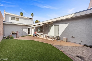 Back of house featuring a lawn, stucco siding, and