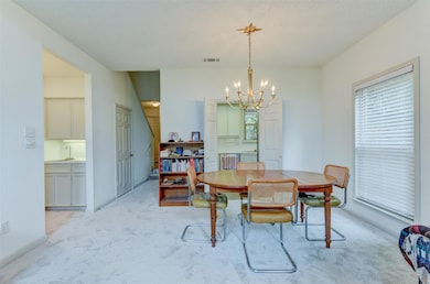 Dining area with light carpet and a chandelier