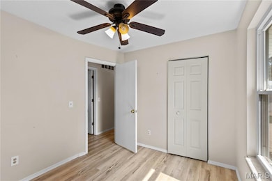Unfurnished bedroom with light wood-type flooring, ceiling fan, and a closet