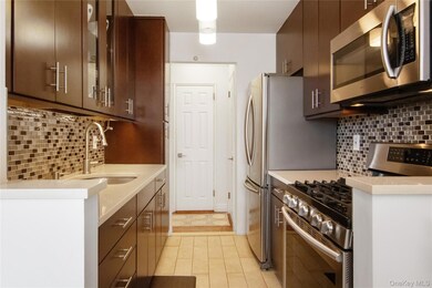 Kitchen with backsplash, appliances with stainless steel finishes, light stone counters, and modern cabinets