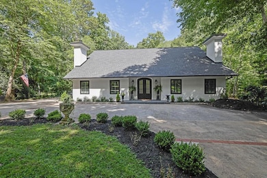 View of front of home with a chimney, covered porch, driveway, and stucco siding