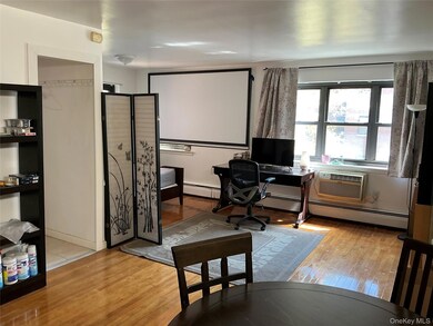 Office area featuring light wood-type flooring, baseboard heating, and a wall unit AC
