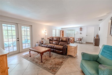 The bonus room features neutral tone walls and tile flooring, and has 2 sets of French doors that open to the screened in lanai and pool.