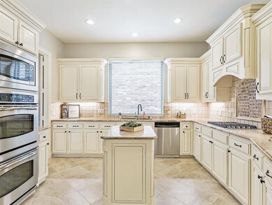 Chef's Kitchen with light granite countertops, stainless appliances, double ovens, 2024 gas cooktop and cream cabinetry--perfect for entertaining friends and family!