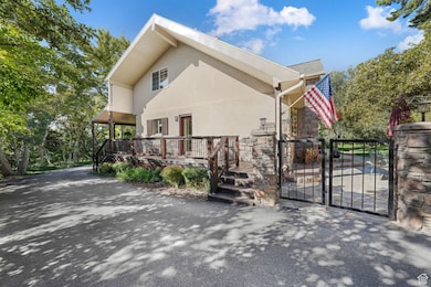 View of property exterior with a gate, stucco siding, a wooden deck, and stone siding