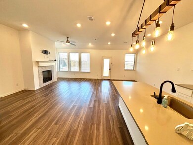 Unfurnished living room with visible vents, a glass covered fireplace, dark wood-type flooring, a sink, and recessed lighting