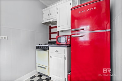 Kitchen featuring white cabinetry, freestanding refrigerator, dark countertops, white gas range, and tile walls