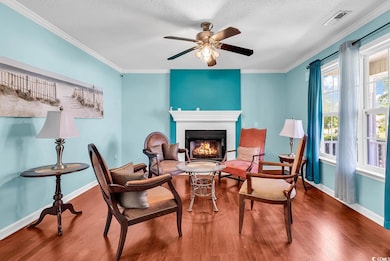 Living room featuring wood finished floors, baseboards, a glass covered fireplace, ornamental molding, and a textured ceiling