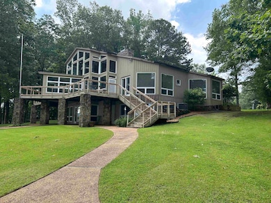 Rear view of house featuring a deck, a yard, stairs, and stone siding