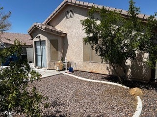 Rear view of property featuring stucco siding and a tiled roof