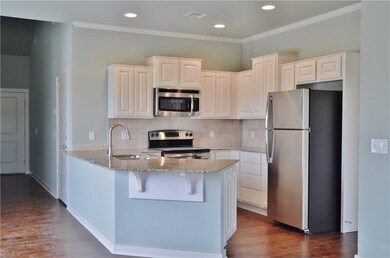 Kitchen with hardwood floors, stainless steel appliances and granite countertops.