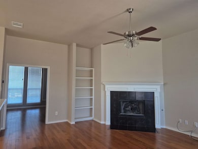 Unfurnished living room featuring dark wood finished floors, a fireplace, and ceiling fan
