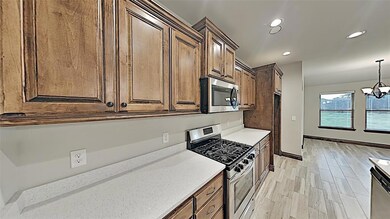 Kitchen with stainless steel appliances, recessed lighting, a chandelier, hanging light fixtures, and light stone counters