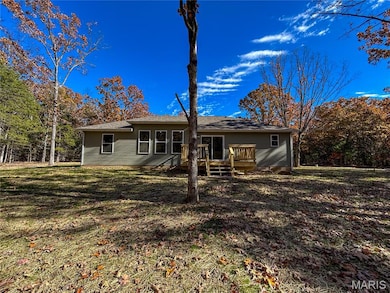 Rear view of property with a deck and a yard
