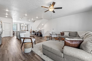 Living room featuring a textured ceiling, dark wood finished floors, and ceiling fan