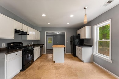 Kitchen featuring black appliances, under cabinet range hood, a sink, healthy amount of natural light, and recessed lighting