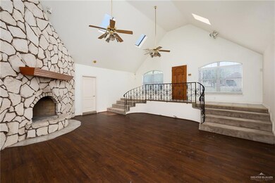 Unfurnished living room with stairway, a skylight, ceiling fan, wood finished floors, and high vaulted ceiling