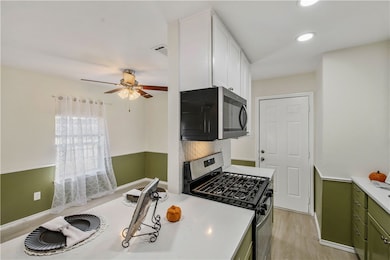 Kitchen featuring appliances with stainless steel finishes, green cabinetry, light wood-style floors, recessed lighting, and white cabinetry